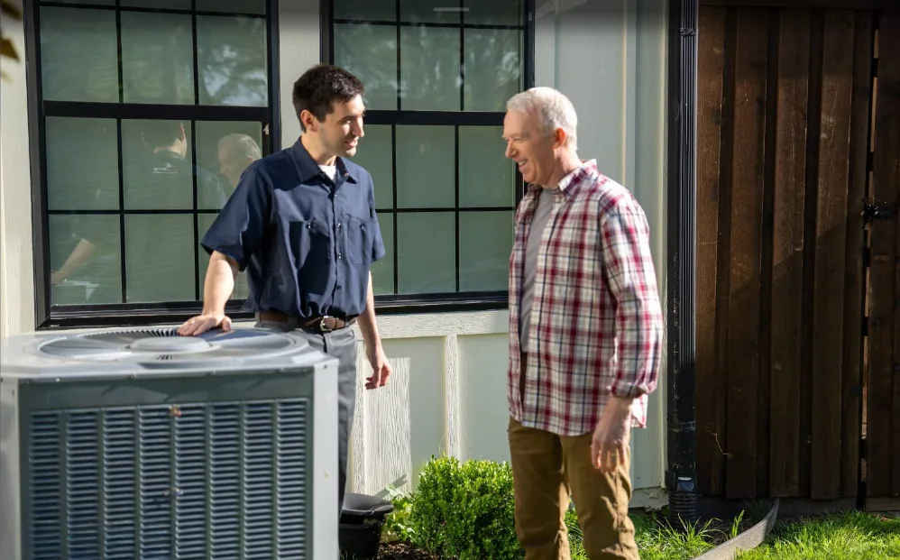 Technician with homeowner next to outdoor AC unit after service